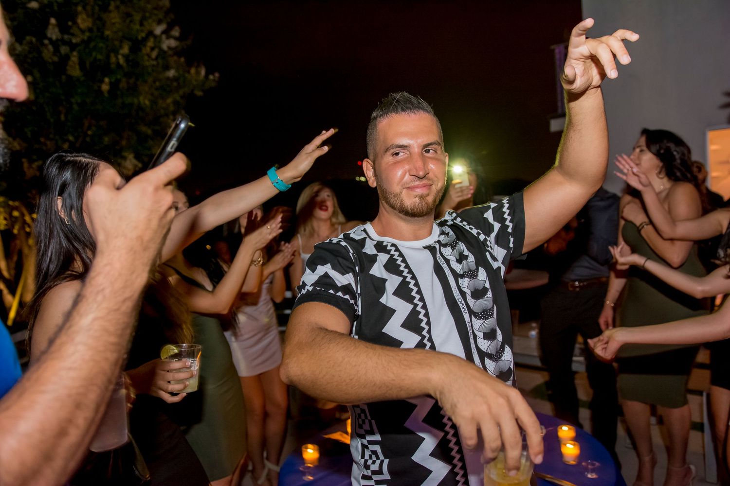 Energetic dance party scene with people celebrating under nighttime lighting.