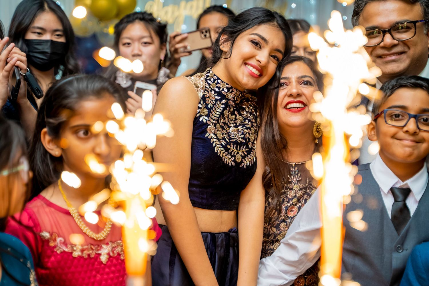 Celebratory moment captured with sparklers and festive decorations at an indoor party.