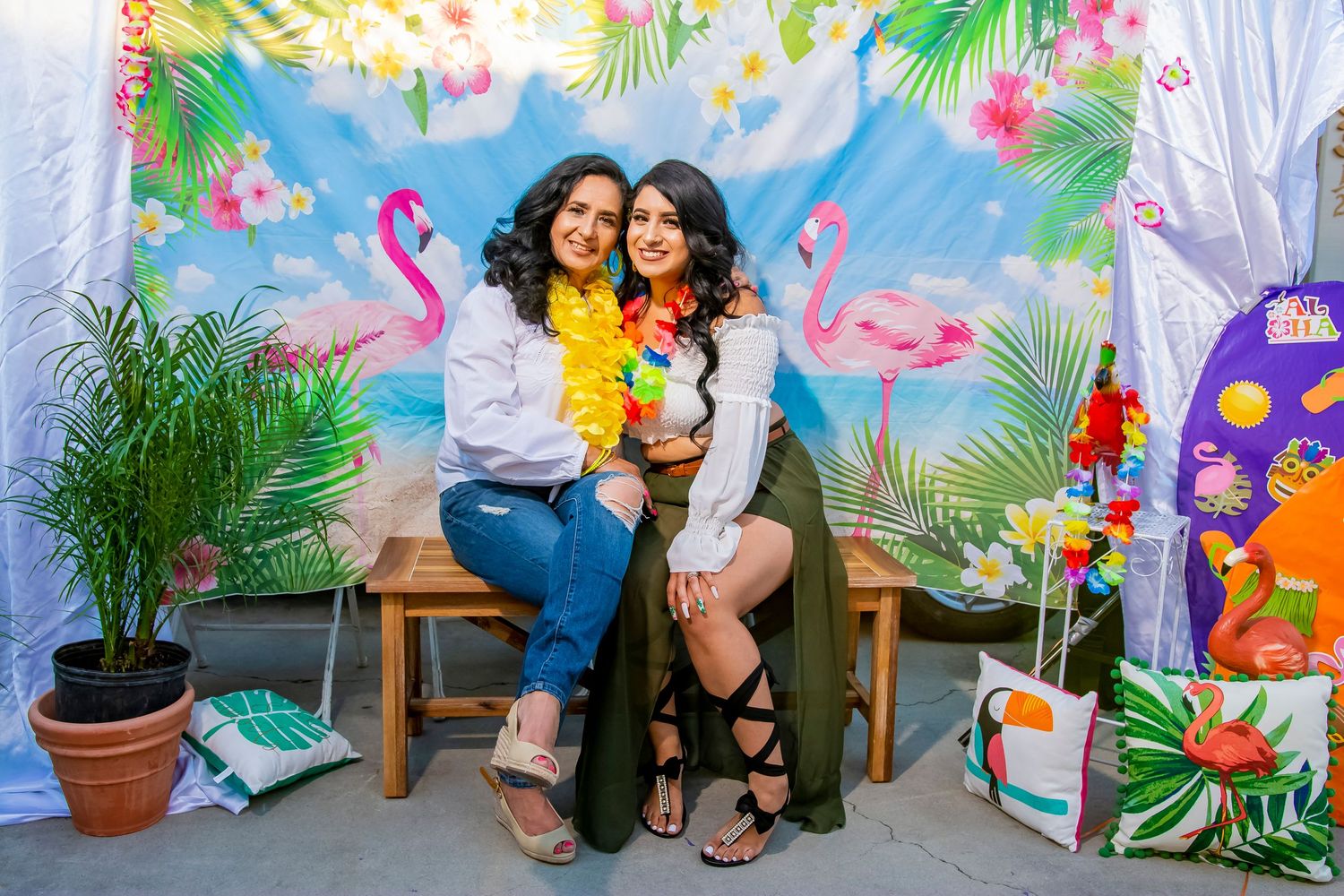 Tropical themed photo booth setup with flamingo decorations and potted plants.