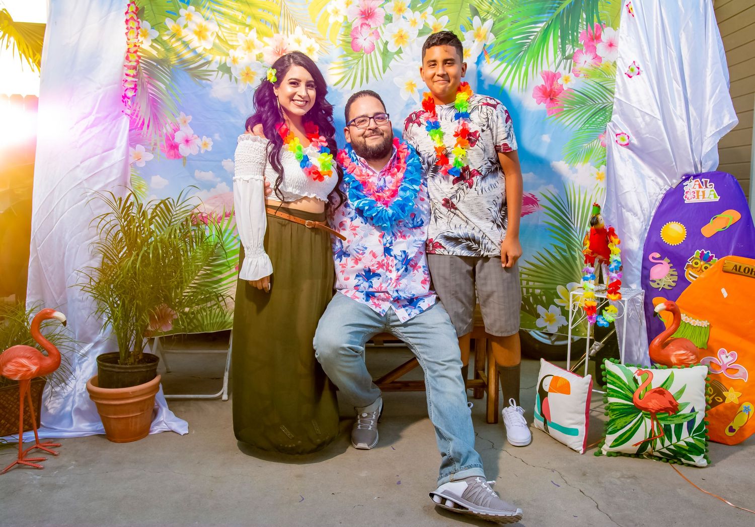 Tropical themed party with guests in Hawaiian leis posing against a floral backdrop.