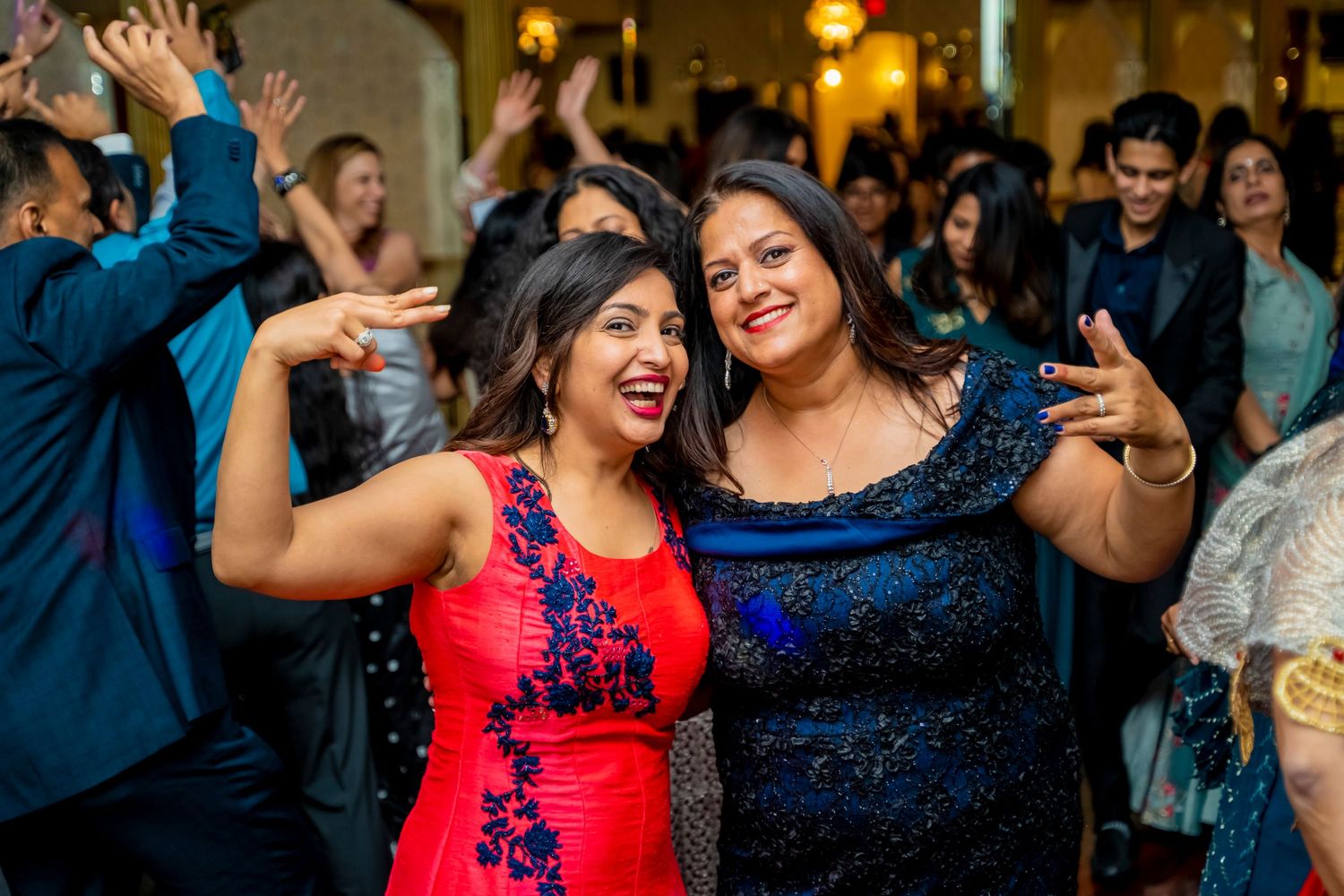 Two guests in elegant dresses share a joyful moment on the dance floor.