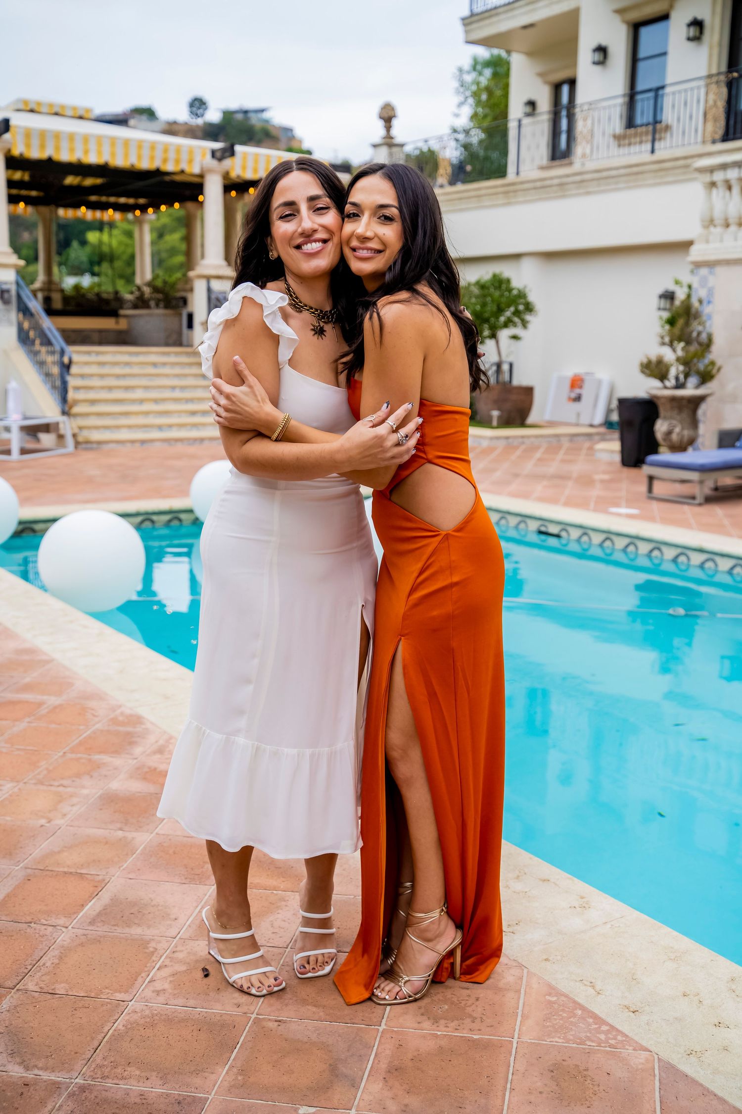 Poolside portrait at an elegant venue with Spanish-style architecture in the background.