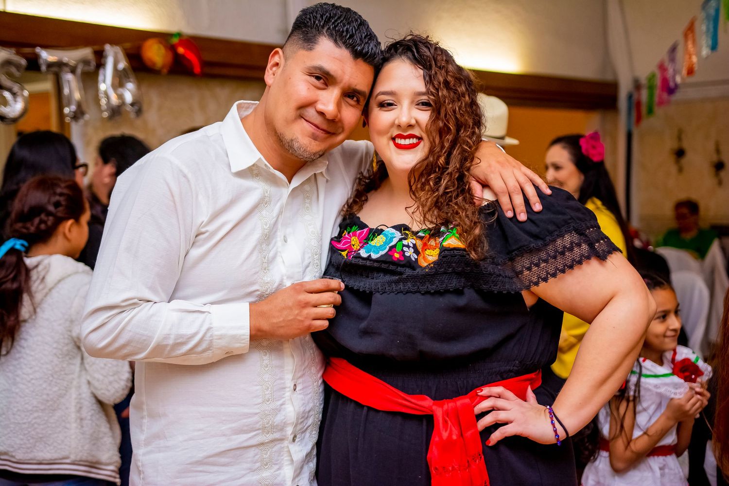 A couple posing at a festive party with Mexican-themed decorations.