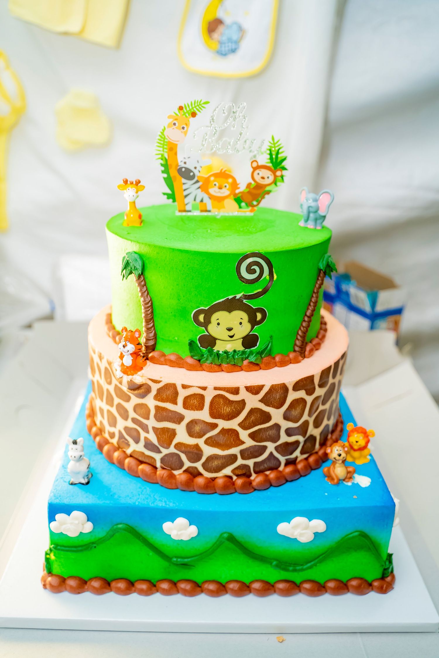 Three-tiered safari themed baby shower cake with jungle animals and giraffe print.