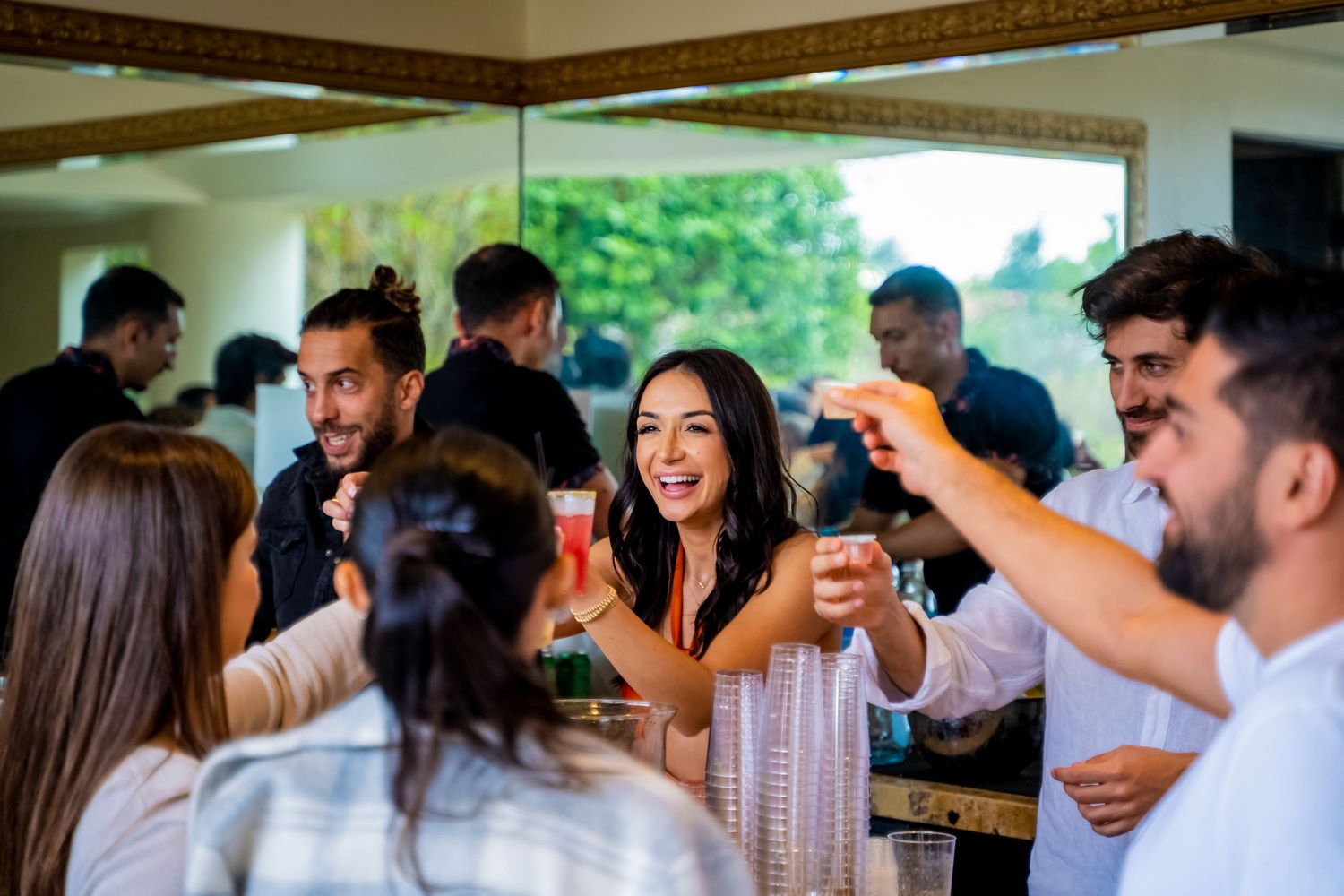 Lively party guests raise their drinks in celebration at an indoor gathering.