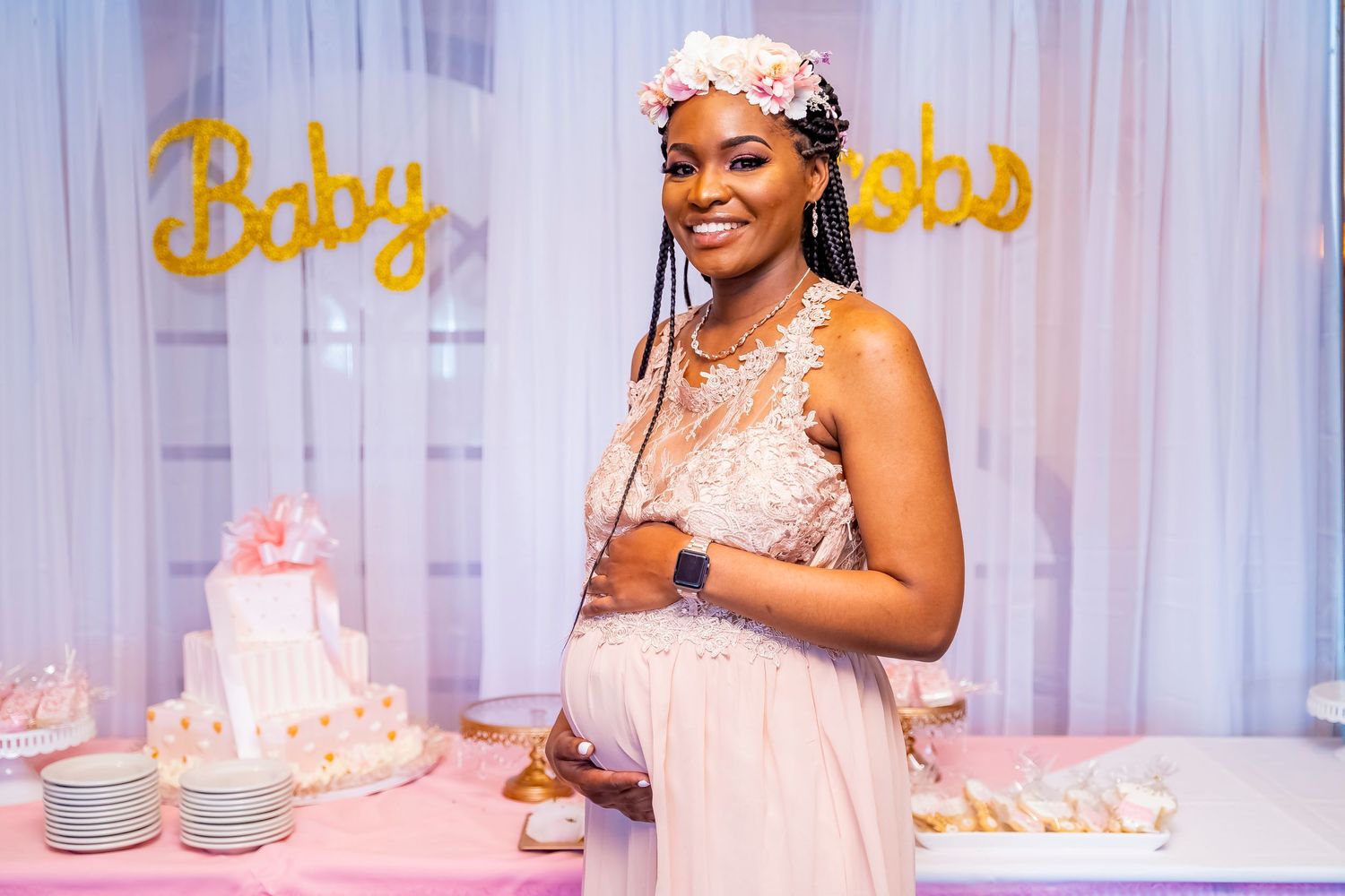 Baby shower setting with pink decorations and 'Baby' text on white backdrop.