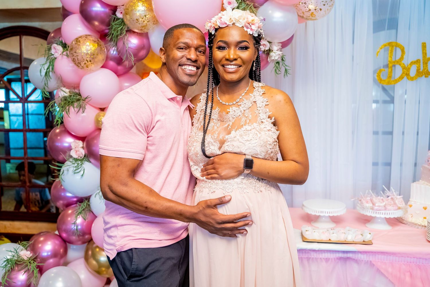 Baby shower celebration with pink and gold balloon arch decorations.