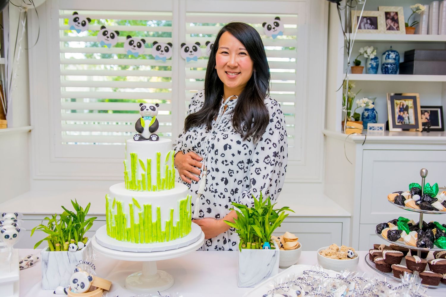 A festive panda-themed celebration with a green and white tiered cake decorated with bamboo designs.