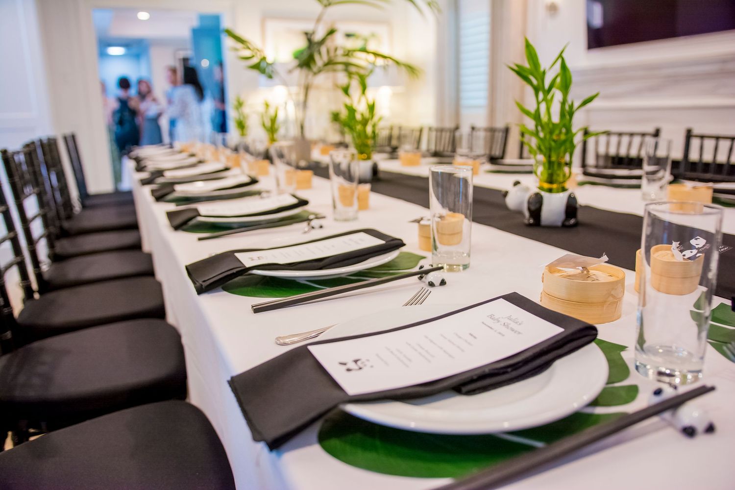 Elegant table setting with green placemats, white plates and bamboo centerpieces.