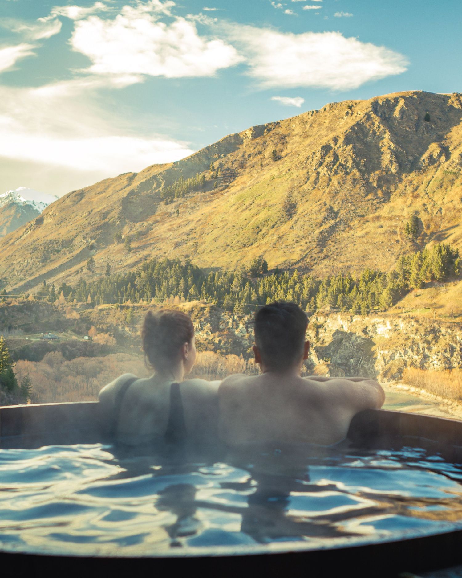 Hot spring pool overlooking majestic mountain views during golden hour.
