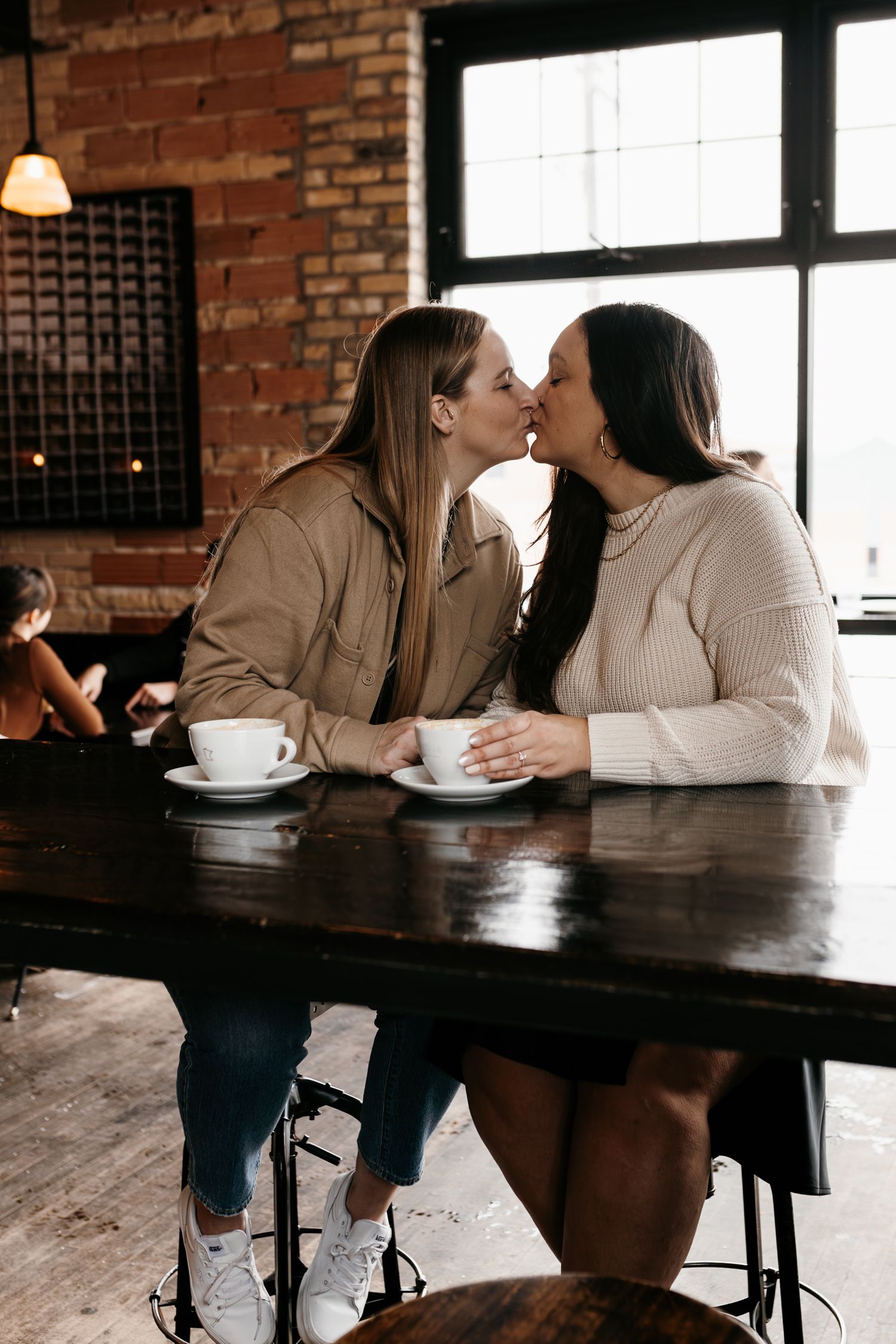 Two people sharing an intimate moment over coffee at a rustic wooden table.