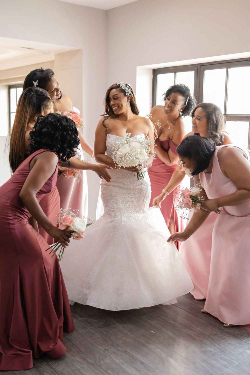 Bridal party in pink dresses shares a joyful moment with bride in white gown.