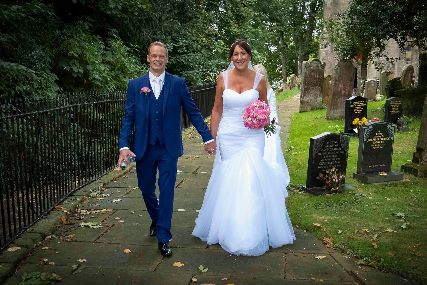 Dave & Hilary walk down the church path hand in hand just after getting married at rockcliffe church carlisle.