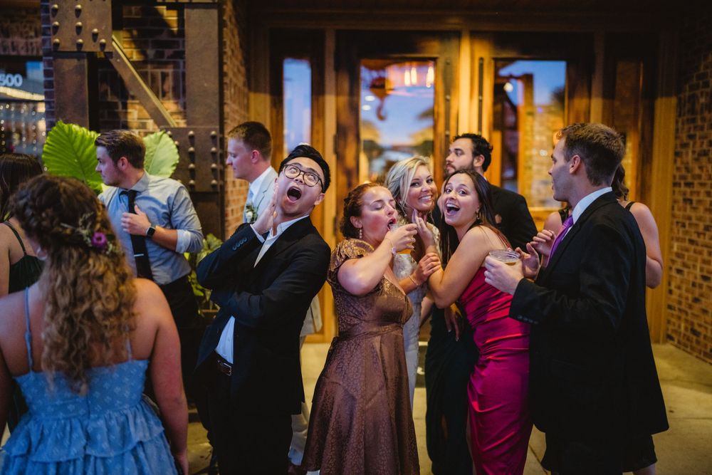 Wedding guests dancing and celebrating at an indoor reception.
