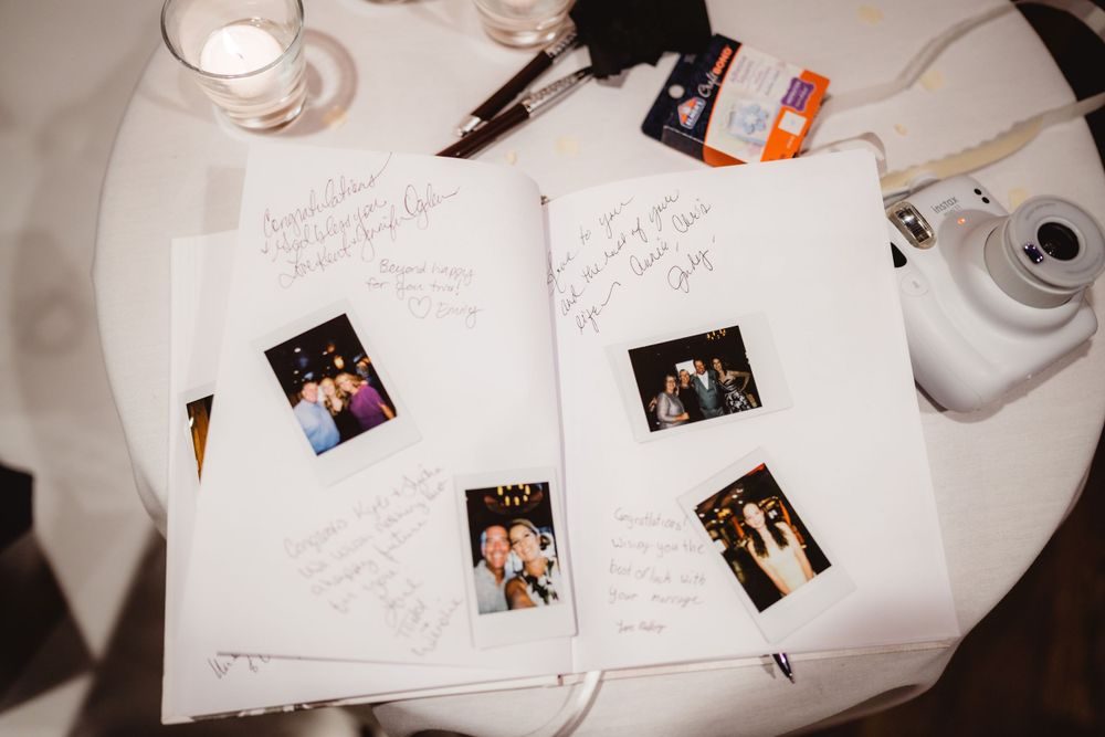 A guest book table with polaroid photos and handwritten messages at a wedding reception.