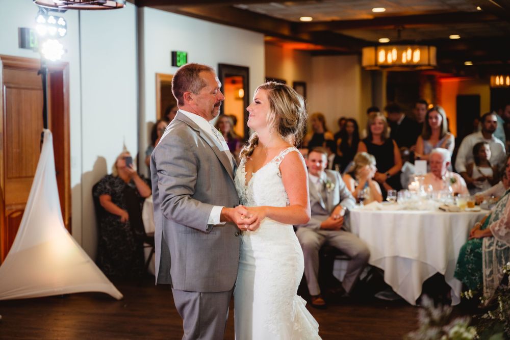 Couple sharing an intimate dance moment on wooden floor during wedding reception.
