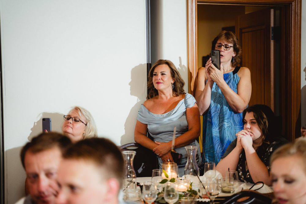 Emotional wedding guests reacting during reception speeches with candlelit table settings.