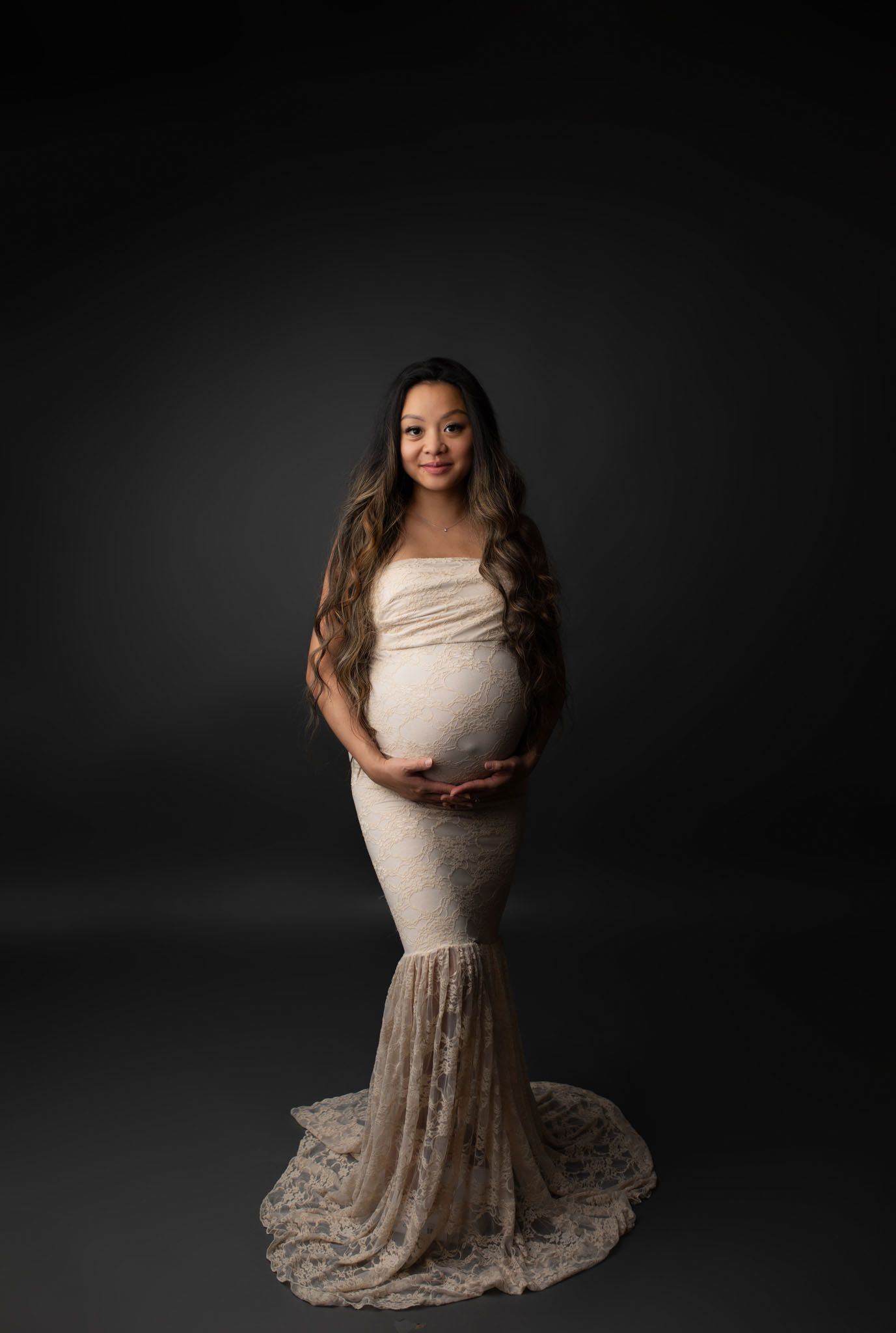 Eden Prairie-maternity-photographer | pregnant woman dark hair wearing floor length champagne color gown dark backgr