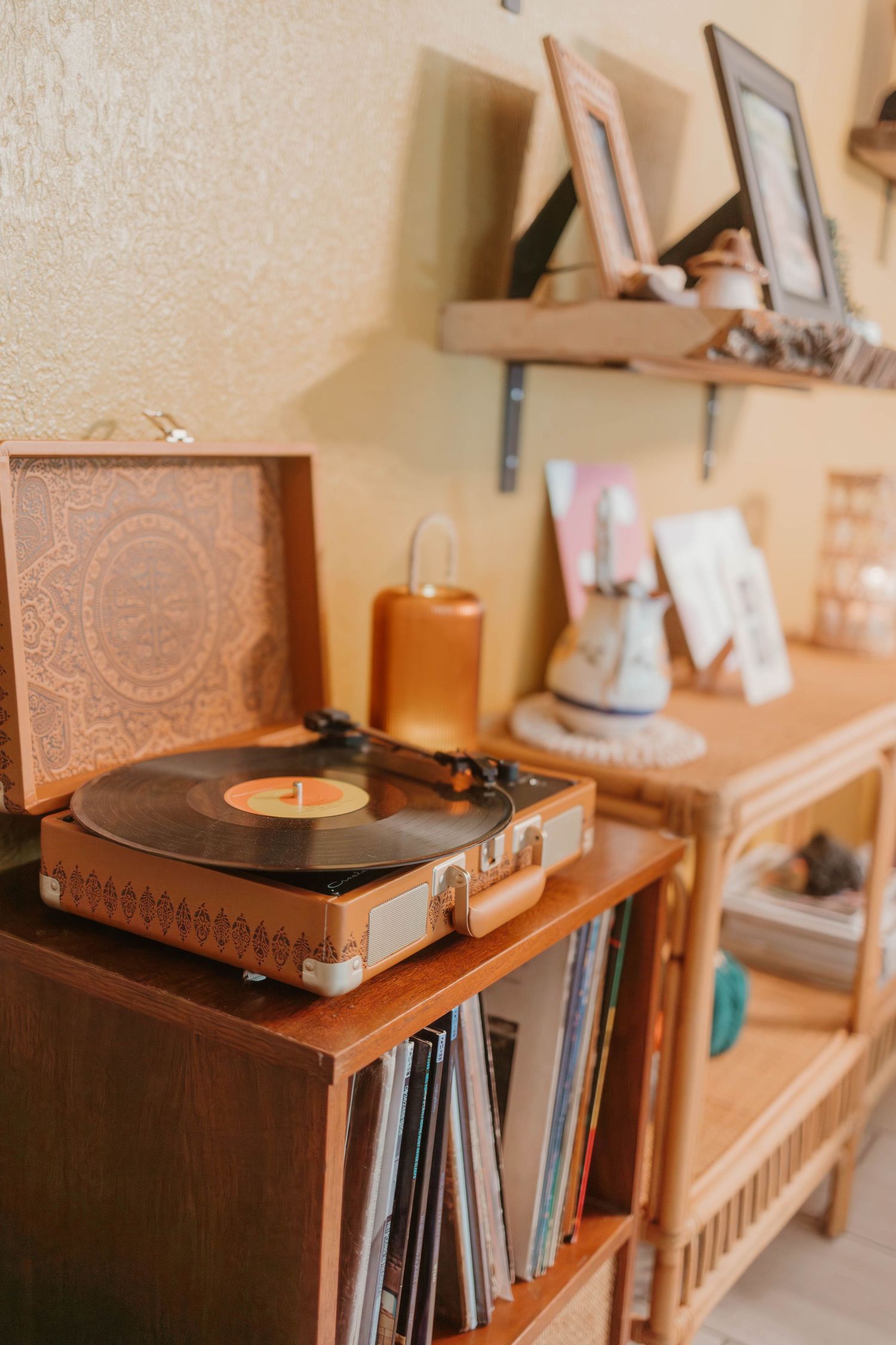 Vintage record player and vinyl collection displayed on wooden shelving with warm lighting.