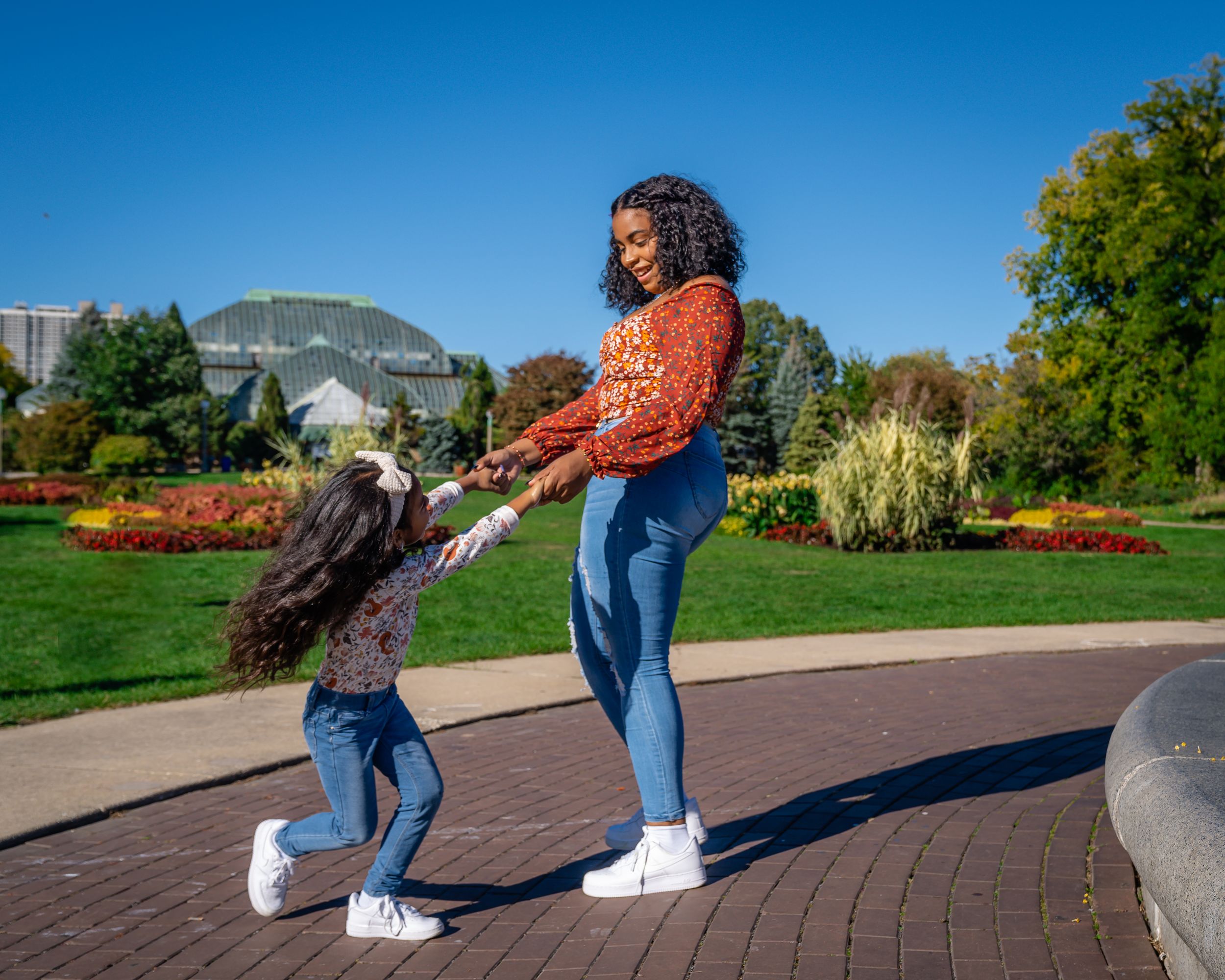 A joyful dance moment captured on a brick path in a vibrant garden setting.