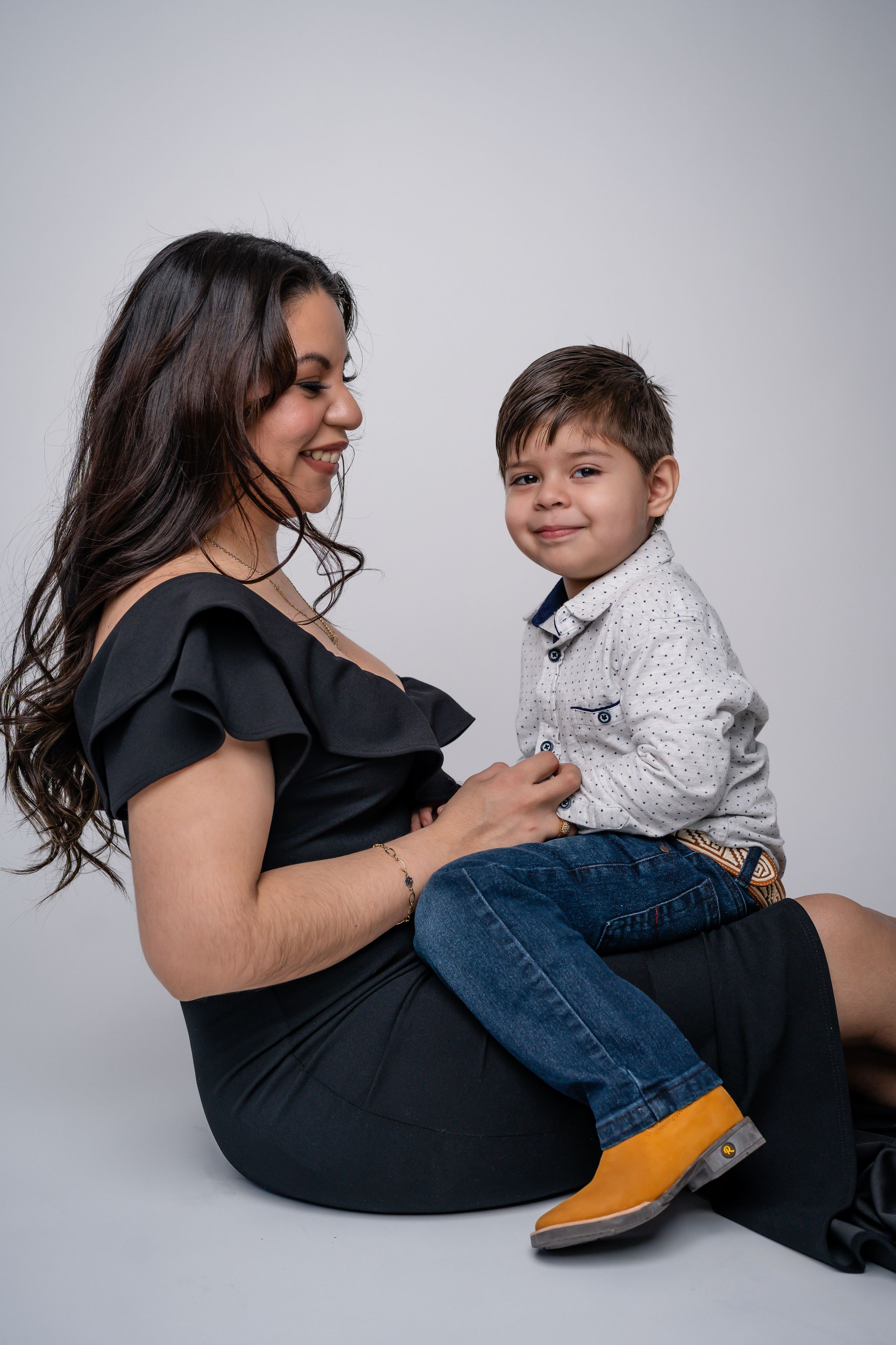 Lifestyle portrait of mother and young son in casual wear against white background.