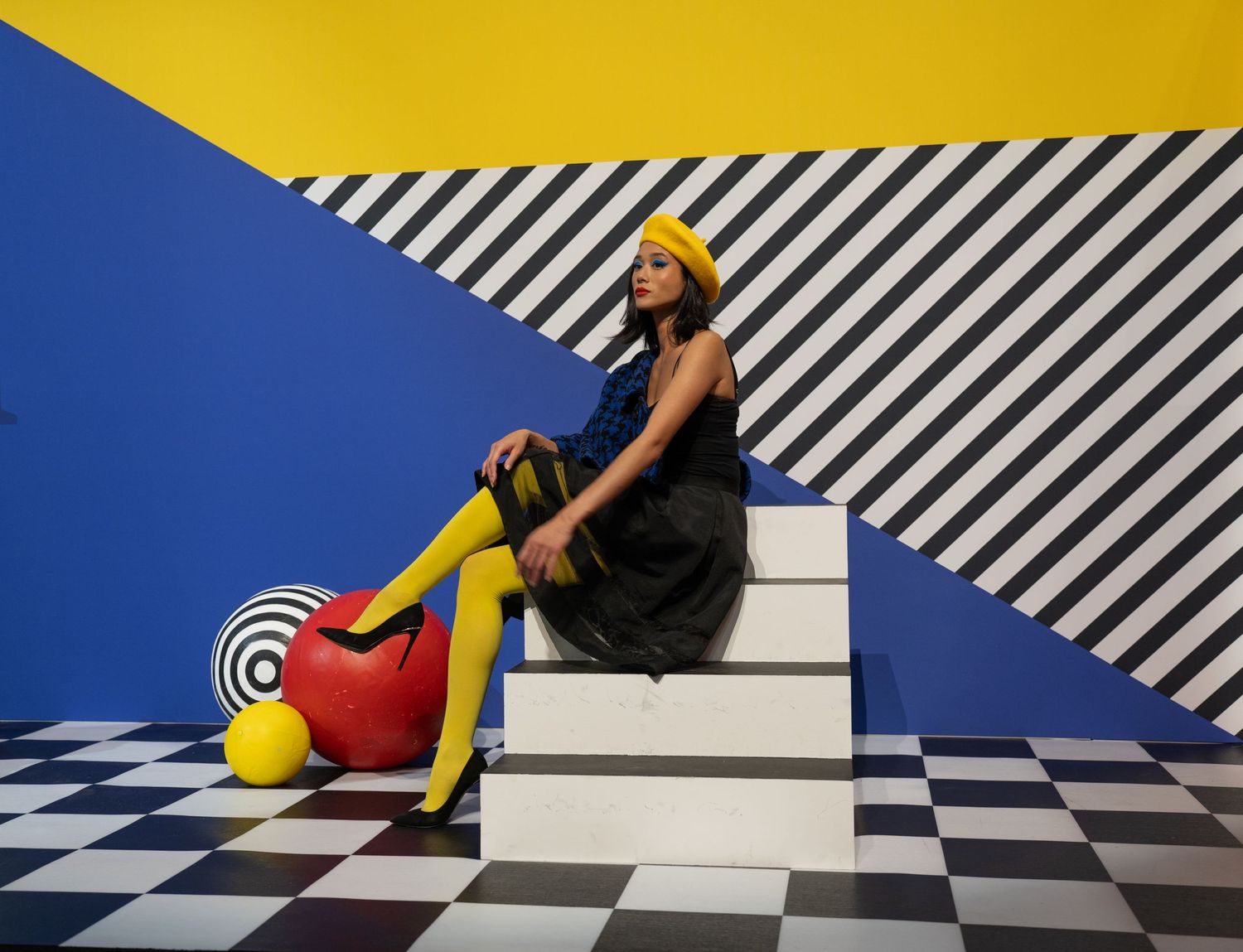 Contemporary fashion scene with vibrant yellow wall, blue accents, and striking black and white patterns.