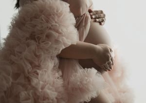 Detail shot of maternity pose with blush pink ruffled tulle fabric.