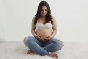 Peaceful maternity pose with mother-to-be sitting cross-legged in casual attire.