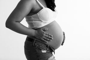 Black and white artistic maternity photo showing side profile in casual attire.