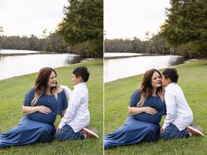 Intimate maternity photo showing couple embracing on grass beside a serene lake.