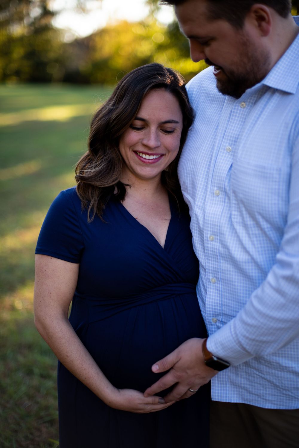 A husband and wife looking down at her pregnant stomach