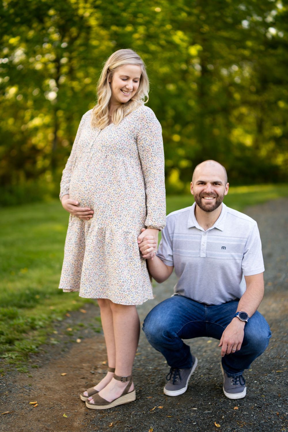 Pregnant women with her husband. She's standing, he's kneeling