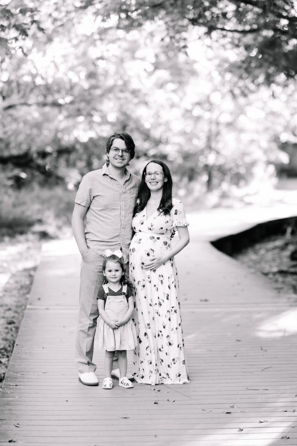 A family of three on a path where the mom is pregnant