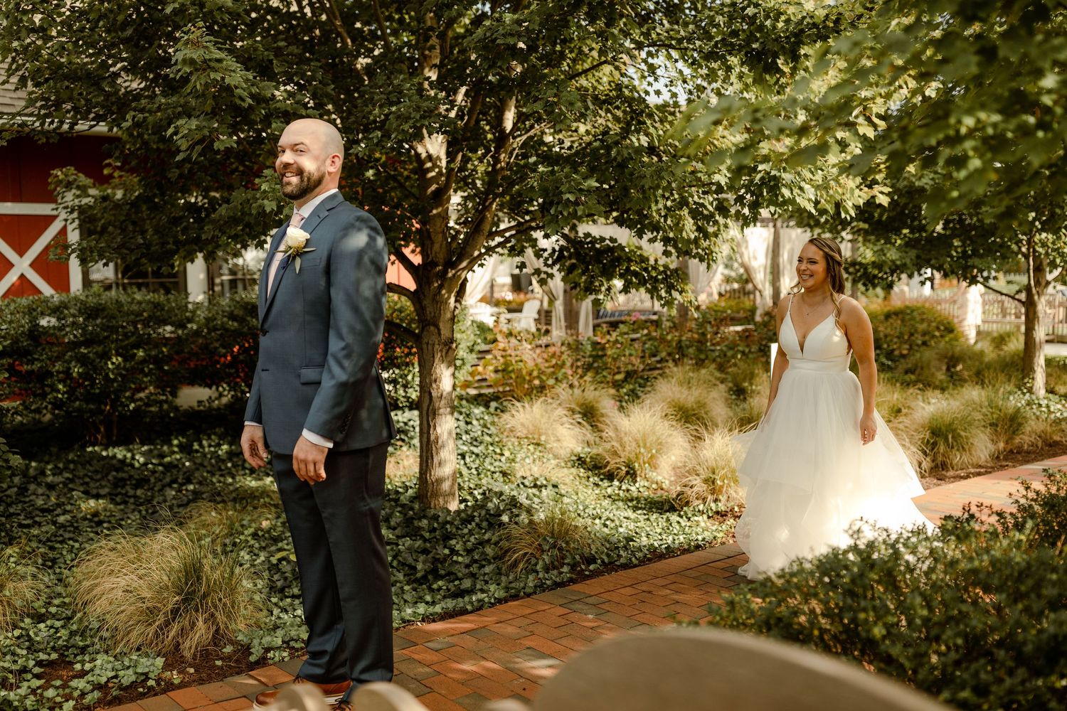 Couple sharing first look moment on brick pathway in lush garden setting.