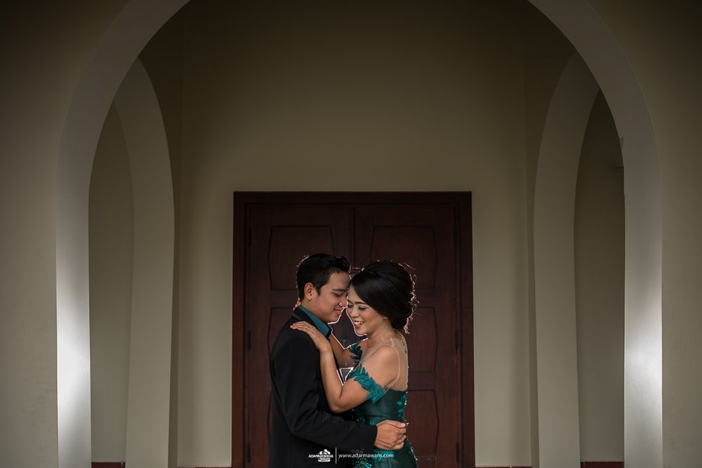 Romantic couple embracing in an archway with dramatic lighting and shadows.