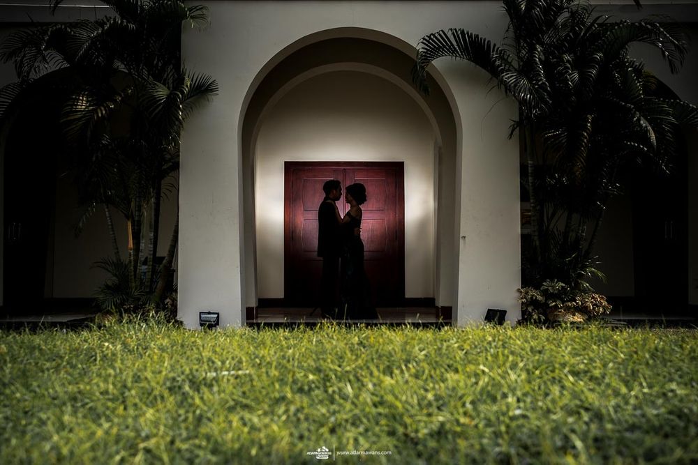 Silhouette of couple through archway against sunset lighting and manicured lawn.