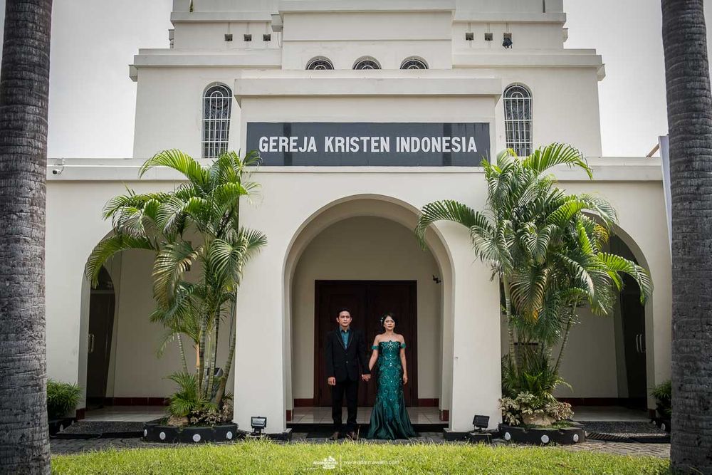 Church exterior with white colonial architecture and palm trees framing the entrance.