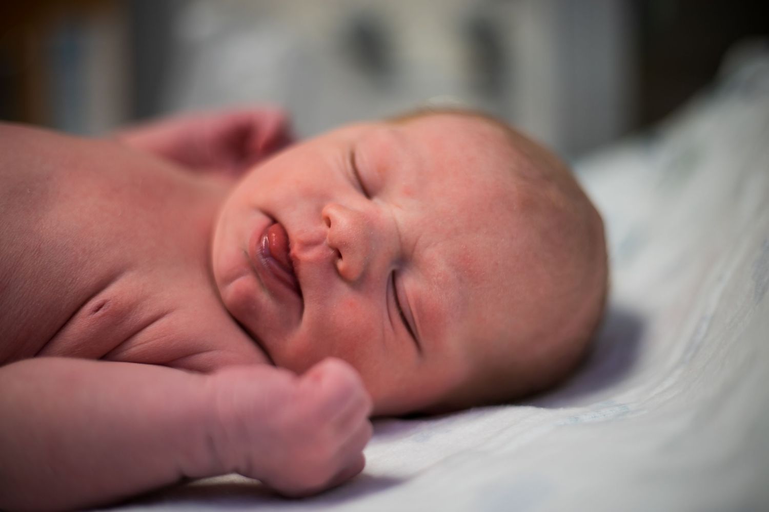 Newborn baby boy sticking out his tongue while he is laying in the hospital warmer just after birth in Sioux City, IA.