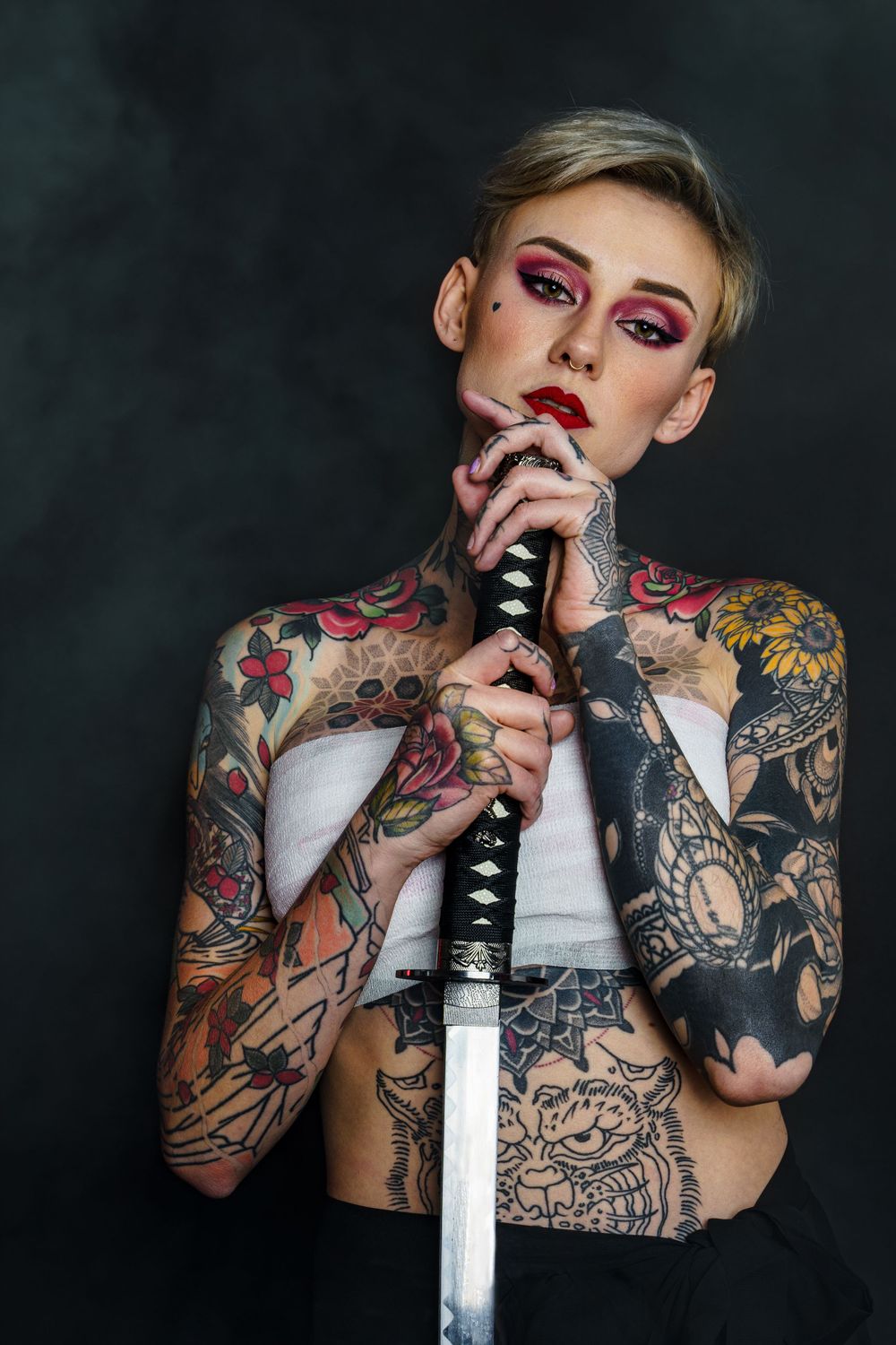 Artistic portrait series featuring tattoos and dramatic makeup against dark background.