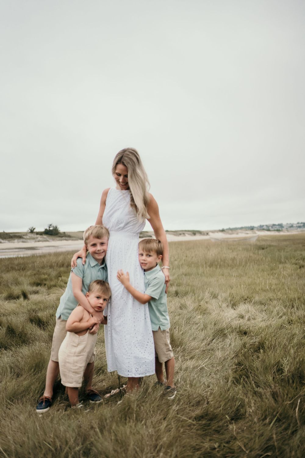 White dress and children playing in coastal grassland setting.