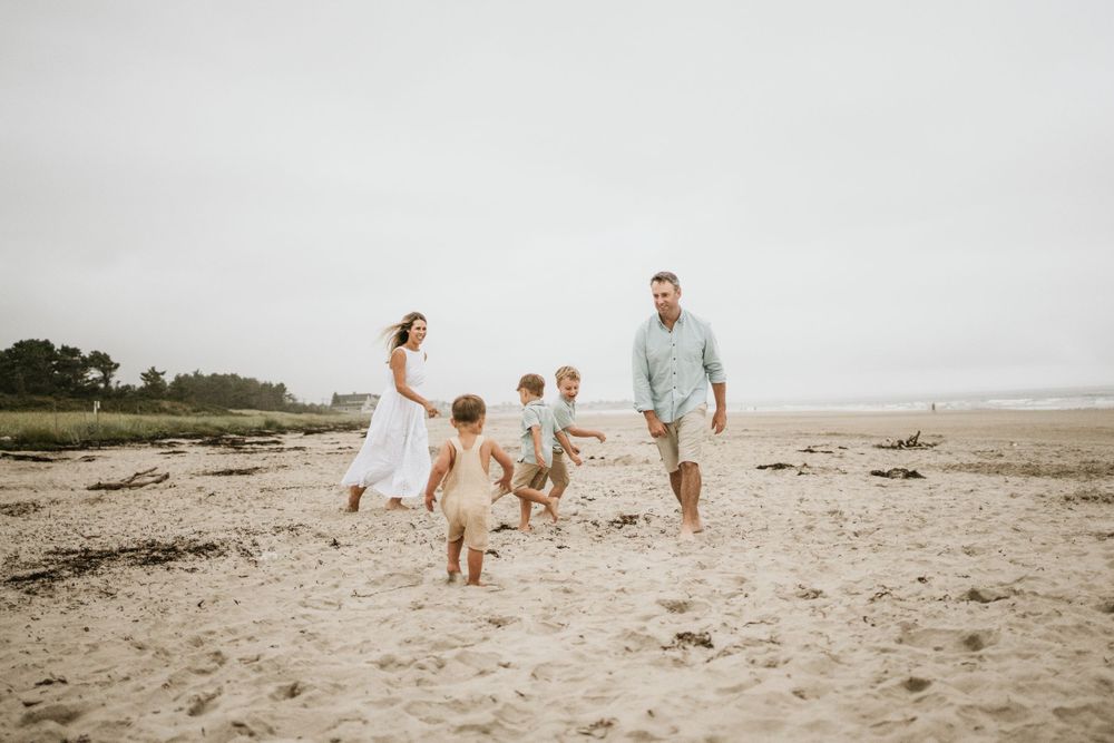 Family running and playing together on sandy beach.
