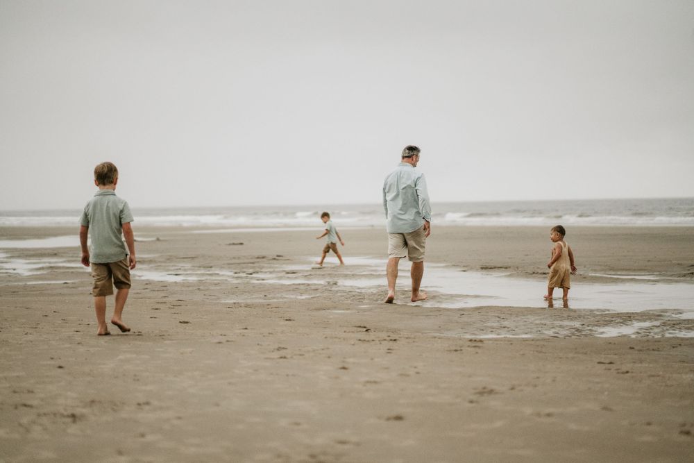 People walking and playing on misty beach shore.