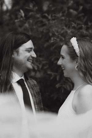 Black and white photo of smiling bride and groom looking at each other outdoors.