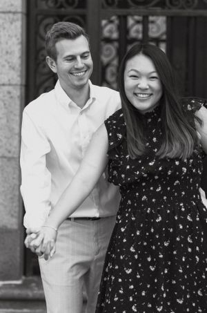 Black and white portrait of smiling couple holding hands and laughing together during engagement session.