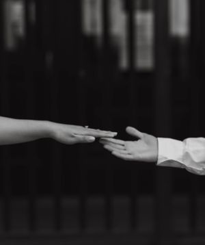 Black and white photo of a couple reaching out to hold hands during their engagement session.