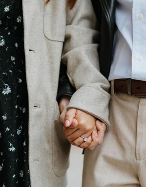 Close-up of engaged couple holding hands showing a sparkling diamond engagement ring on her finger.