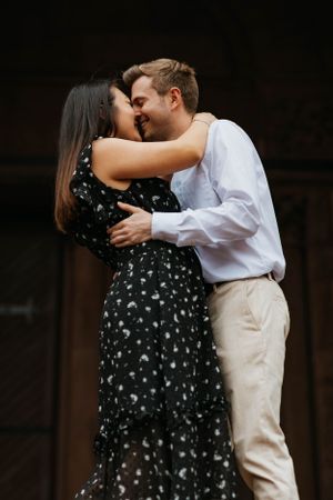 Engaged couple sharing a tender kiss outdoors during their engagement photography session.