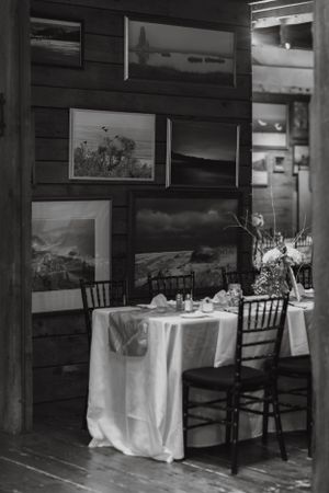 Black and white photo of an elegant small reception table set beneath framed landscape artwork.