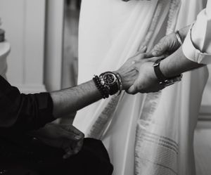 Black and white close-up of hands being tied together in a traditional wedding ceremony ritual.