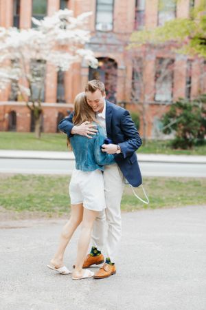 Happy couple embracing and celebrating after a marriage proposal near cherry blossom trees outdoors.